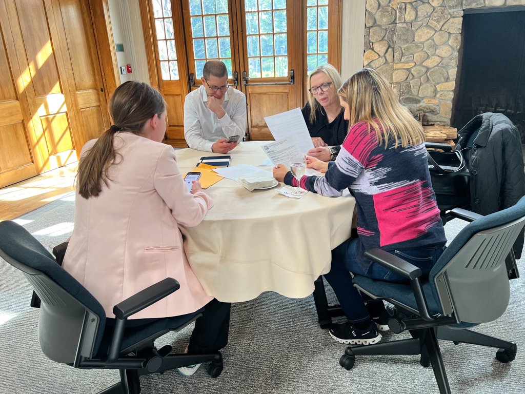 a team of four colleagues at a table reviewing case files during a clue murder mystery team building activity in washington dc