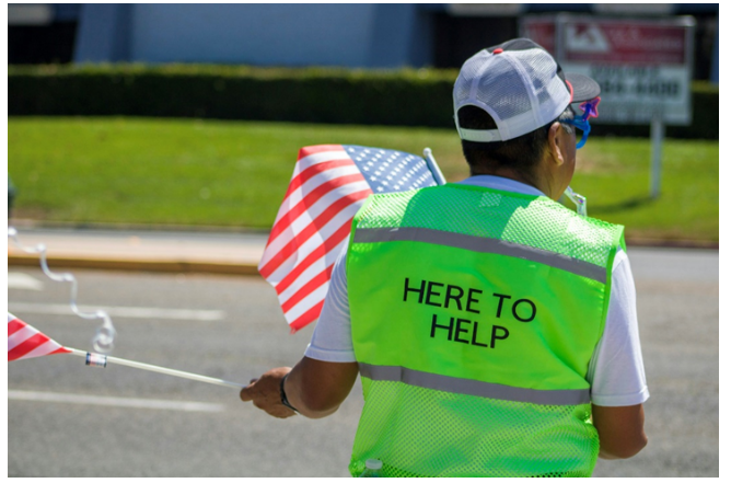 person standing in road with safety vest and flags