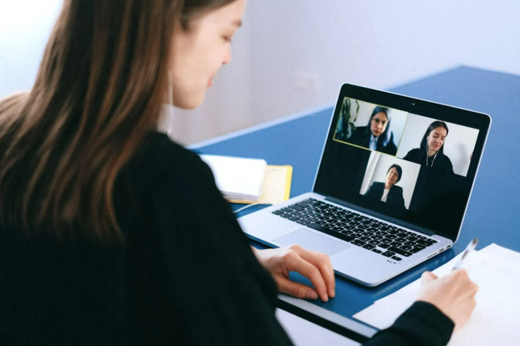 woman at table looking at laptop with meeting on the screen